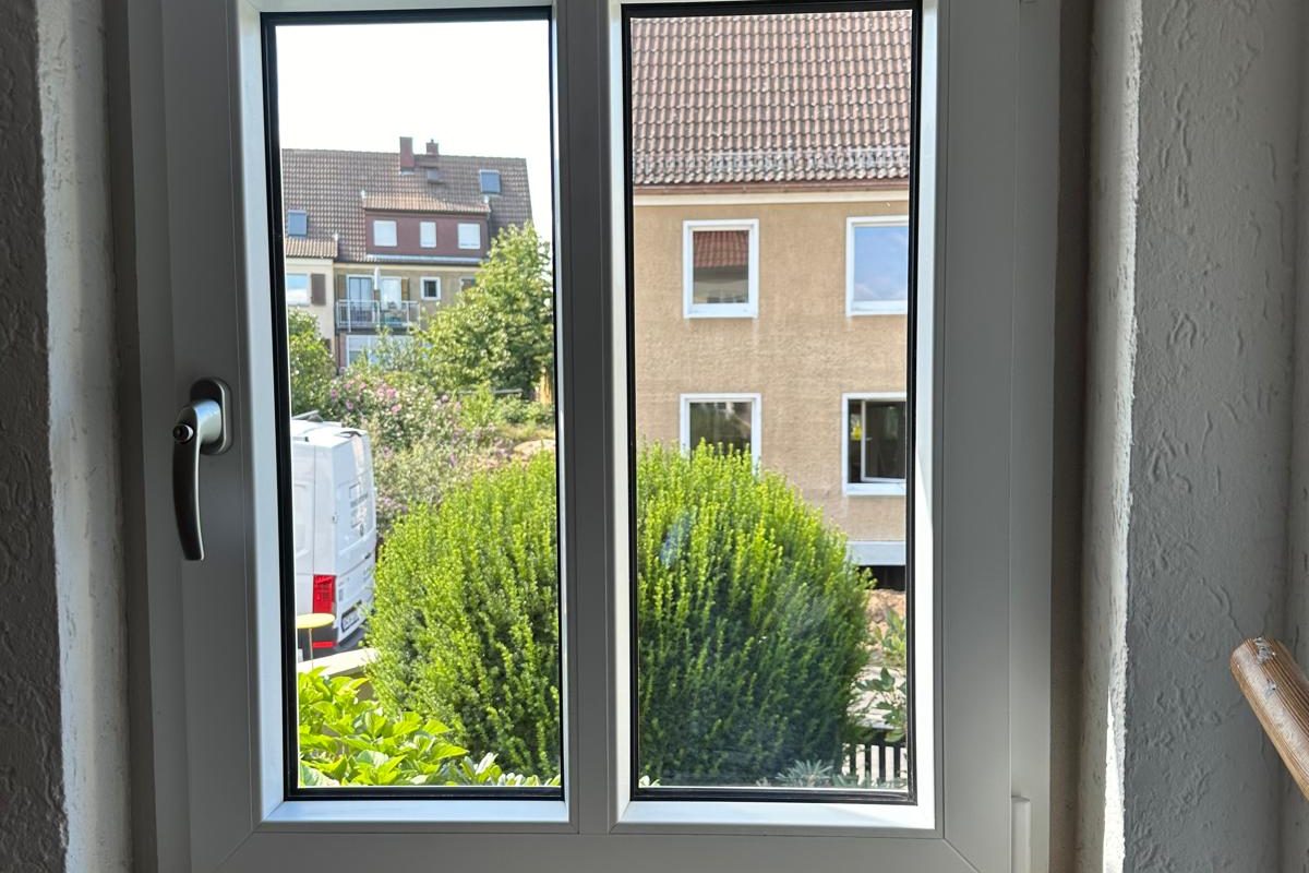 Zweiflügliges weißes Fenster von innen mit Blick in den Garten