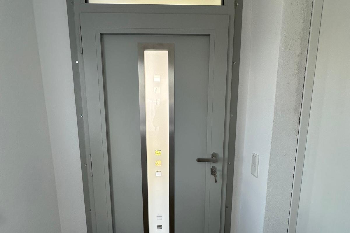 Graue Haustür mit Glasstreifen und Oberlicht im Flur