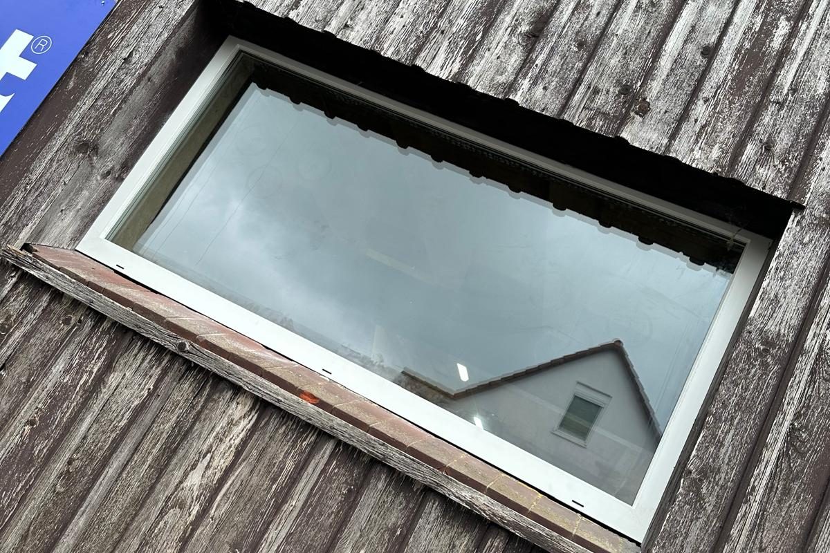 Neues weißes Kunststofffenster an derselben Stelle der Holzschalung