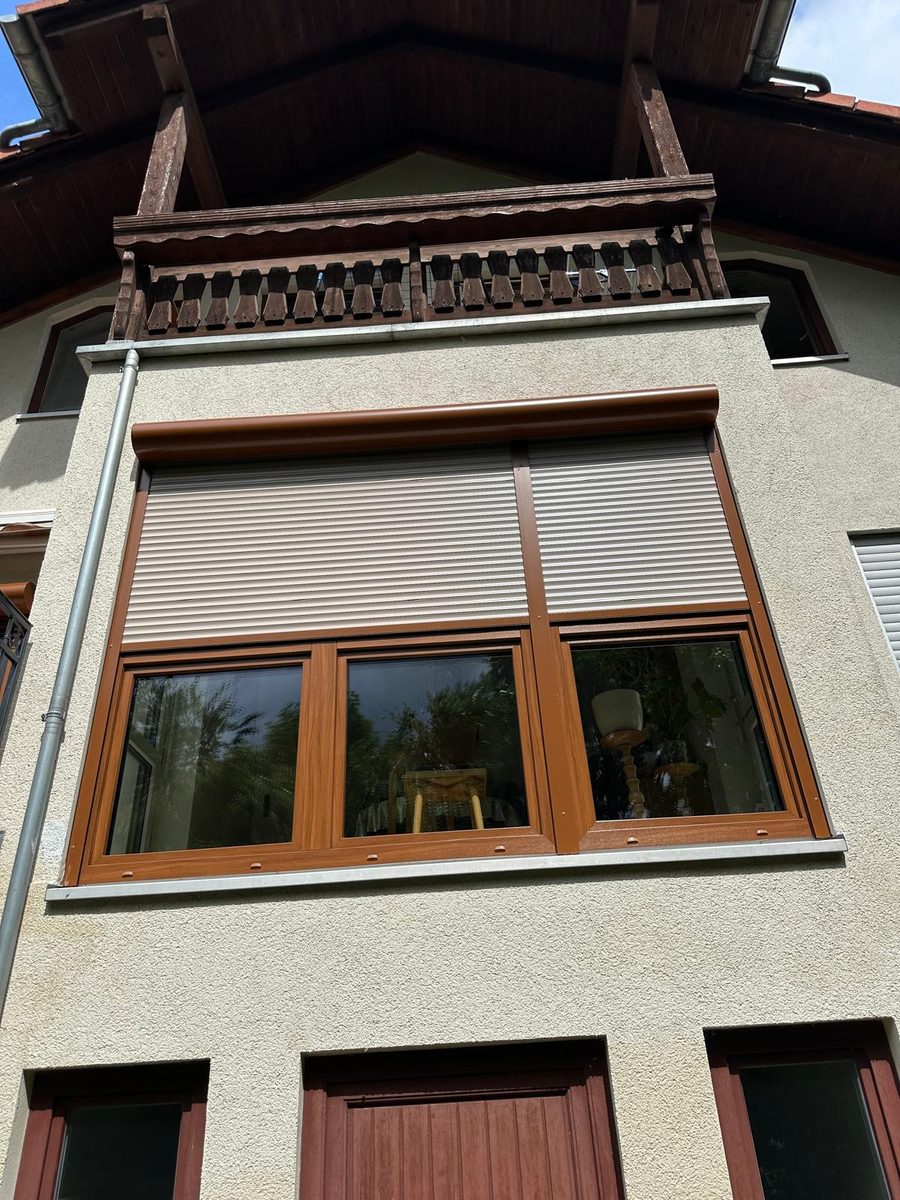 Fassade mit großem Fenster in Holzdekor und zwei hellen Rollläden