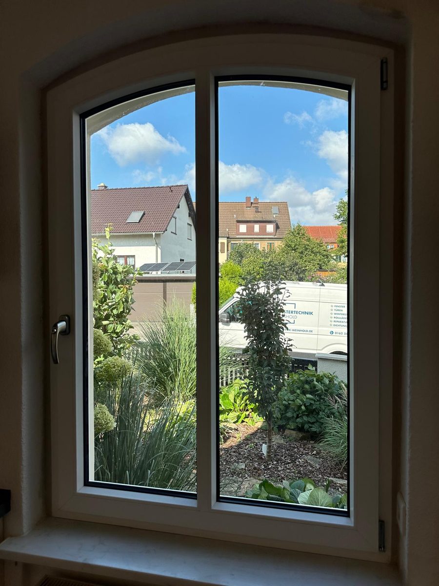 Rundbogenfenster mit zwei Flügeln von innen, Blick in einen Garten