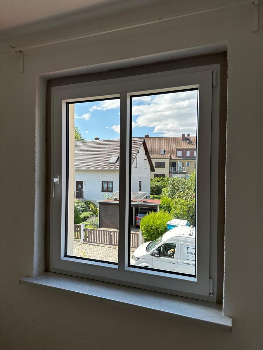 Neues weißes Fenster mit schmalen Rahmen in einer frisch gestrichenen Laibung