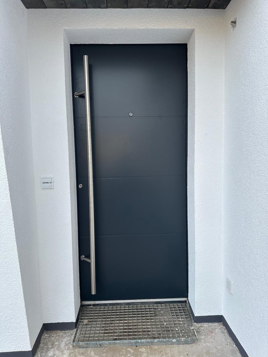 Anthrazitfarbene Haustür mit langem Edelstahl-Stoßgriff