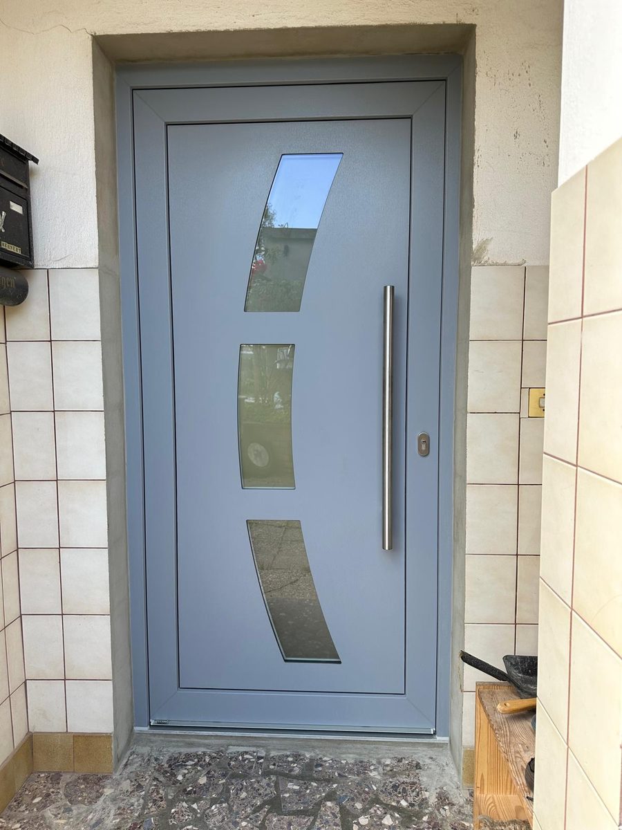 Graue Haustür mit drei geschwungenen Glaseinsätzen und Stangengriff