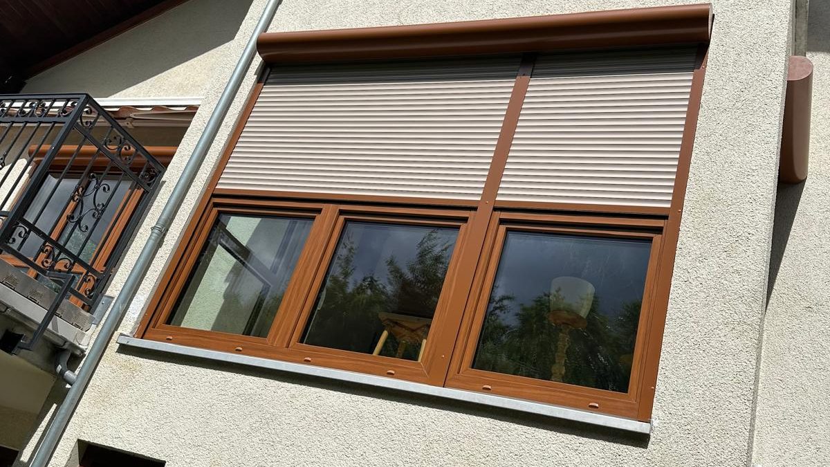 Fenster in Holzdekor mit Rollläden an einer hellen Putzfassade