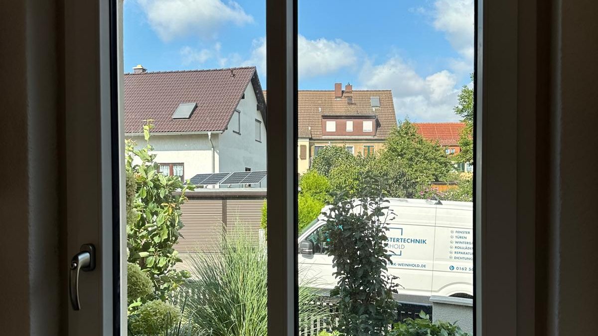 Zweiflügliges Rundbogenfenster von innen mit Blick in einen sonnigen Garten