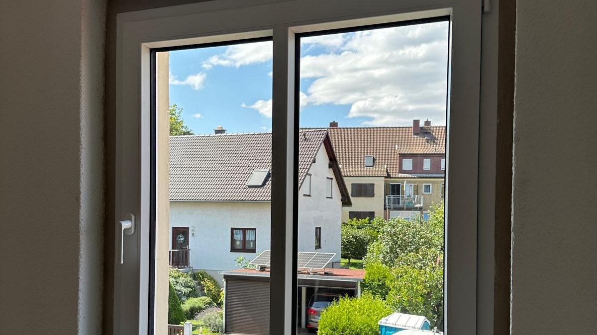 Neues weißes Fenster mit Blick auf Gärten und Häuser der Nachbarschaft